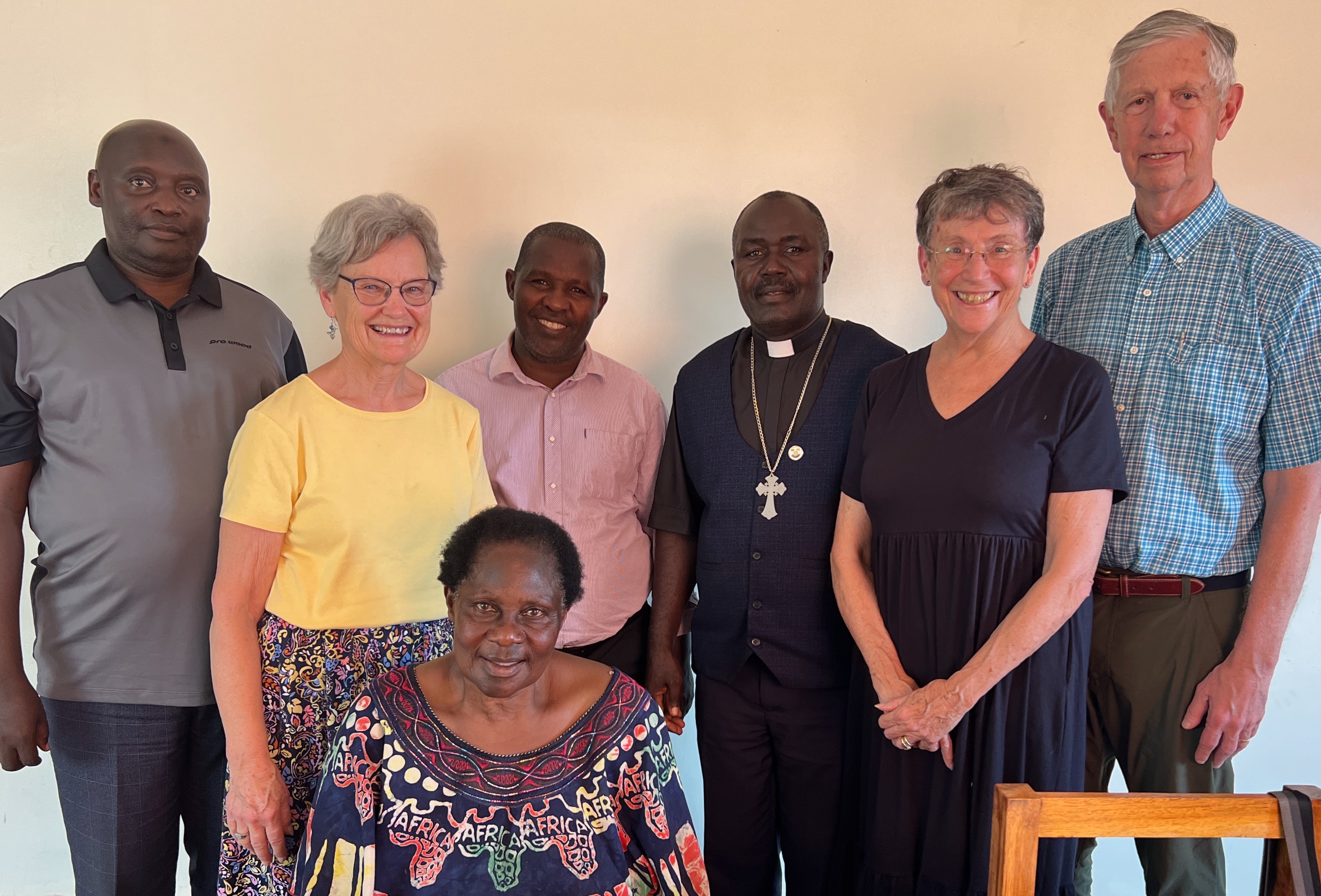 Three Ugandan men, three gray-haired Americans, and one, seated Ugandan woman