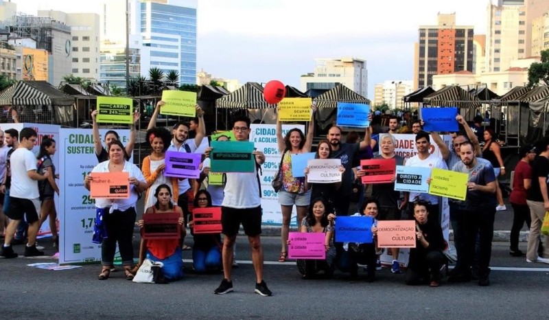 A diverse group of about 35 people pose indoors, smiling, with a banner reading “#BreakFreeFromPlastic América Latina y el Caribe“ above. 