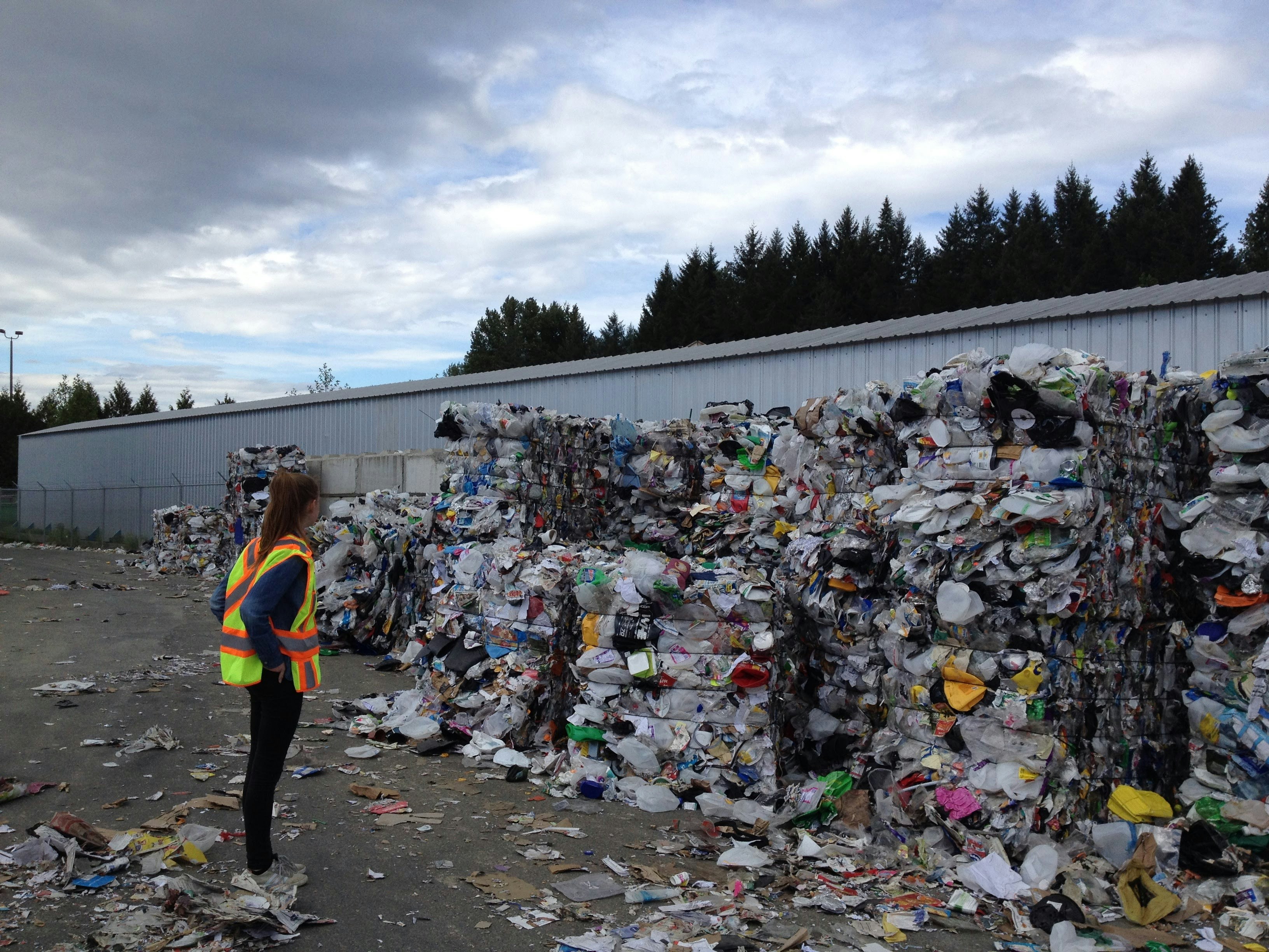 photo of a person standing looking at a pile of plastic trash