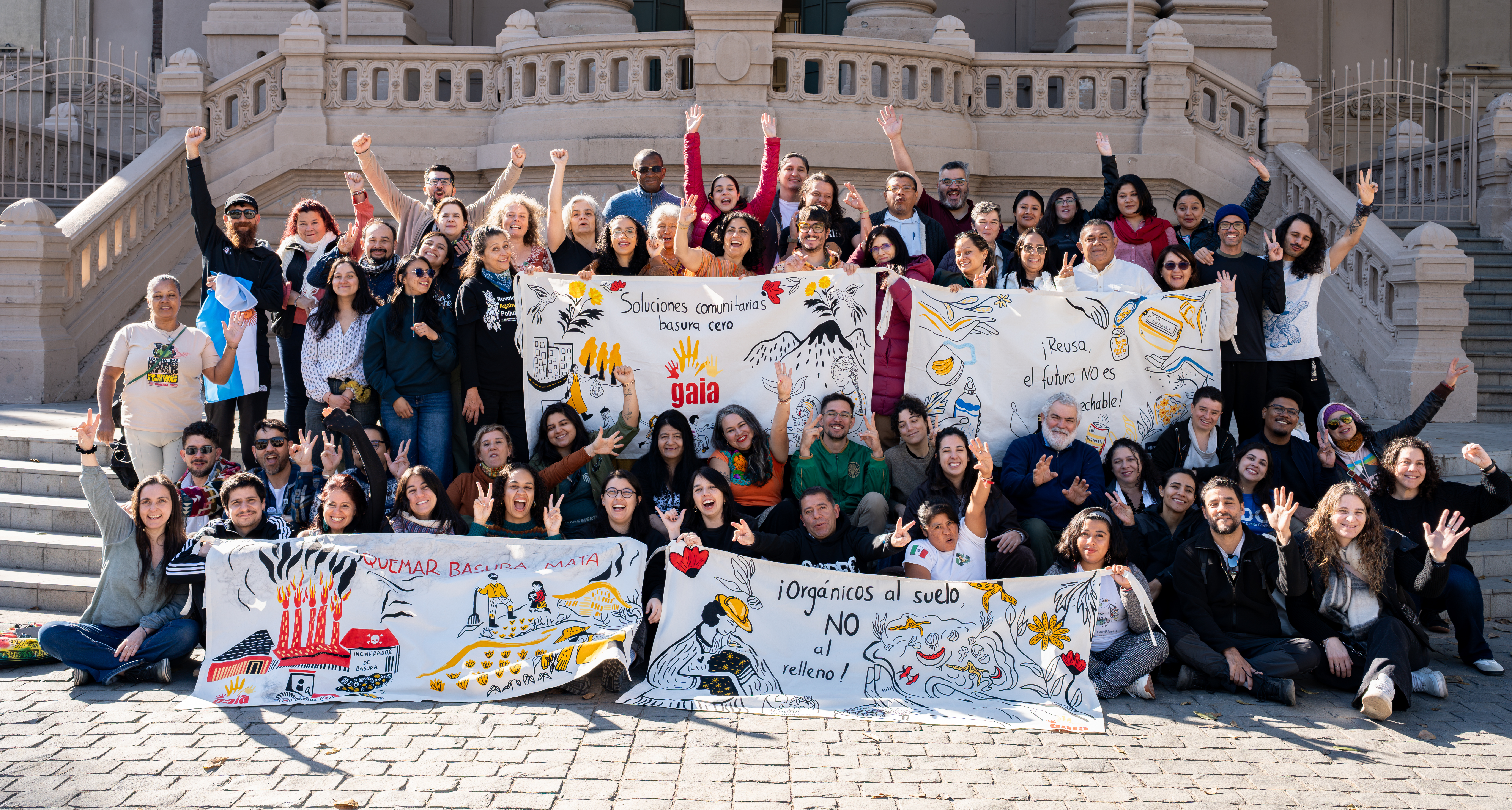 A diverse group of about 35 people pose indoors, smiling, with a banner reading “#BreakFreeFromPlastic América Latina y el Caribe“ above. 