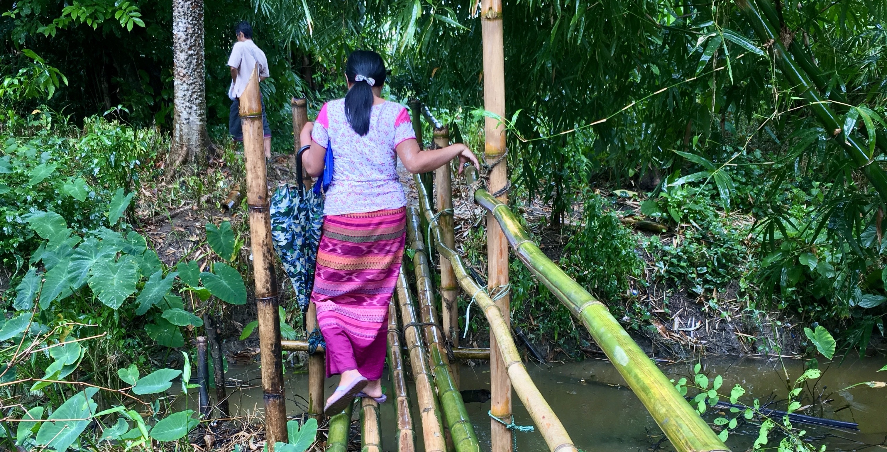 Savings Group participant crossing a man-made bridge in Myanmar