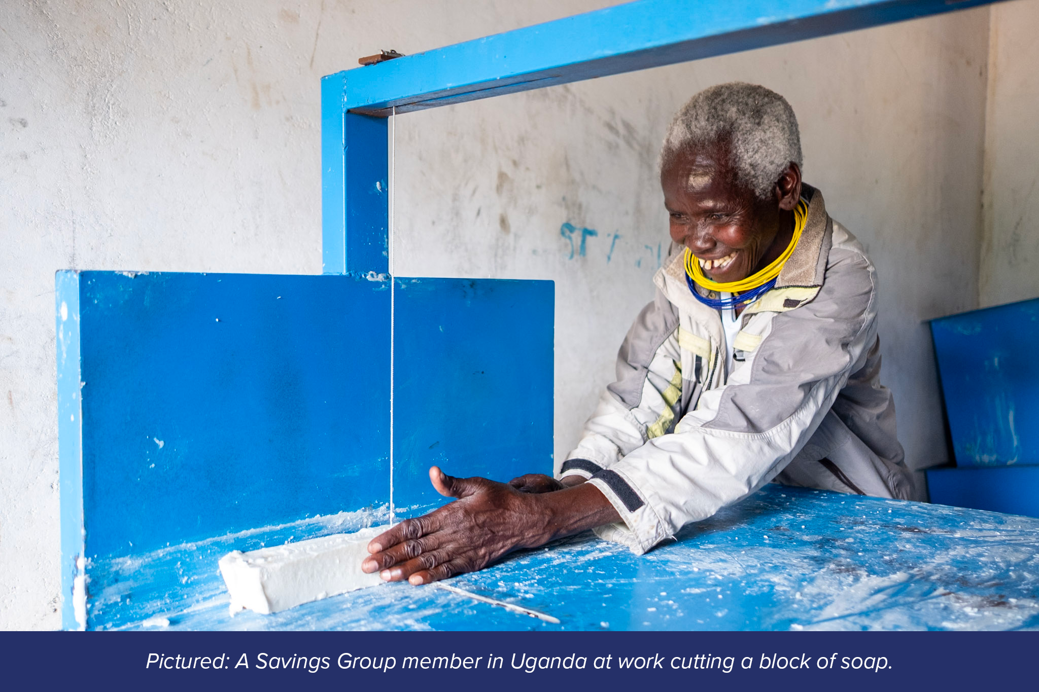 A Savings Group member in Uganda at work cutting a block of soap