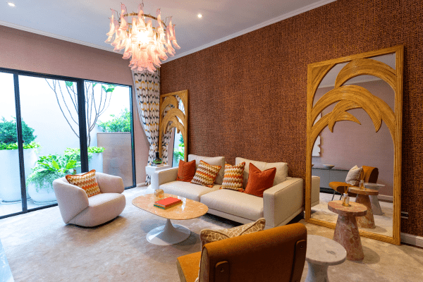 Luxurious Art Deco style living room with mirrored furniture, geometric patterns, gold accents, and plush seating under a statement chandelier